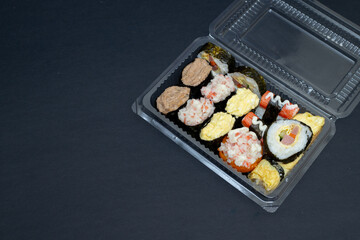 Big sushi set in transparent plastic box. Isolated on black background. Japanese food.