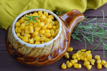 Corn in a pot on a wooden background.
