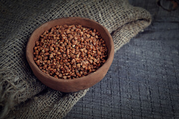 Buckwheat in a clay plate on a wooden background.Healthy food.