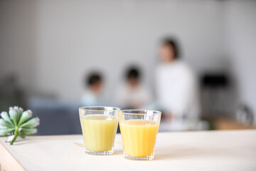 家族がいるリビングの木のテーブルにジュースが2つ並んで置いてある　juice living