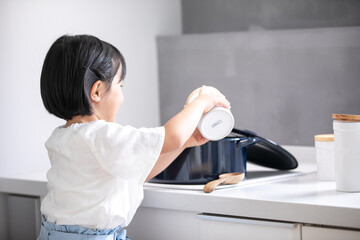 白いキッチンで女の子が青い鍋で料理をしている　girl kitchen 