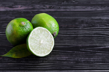 fresh green limes and half a lime on a wooden background of kopi space