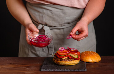Close-up on the preparation of a magnificent burger.  Gastronomy, recipes, menus, fast food. Juicy hamburger
