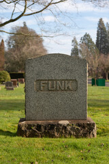 A single cemetery headstone surrounded by grass with the name FUNK chiseled in large letters