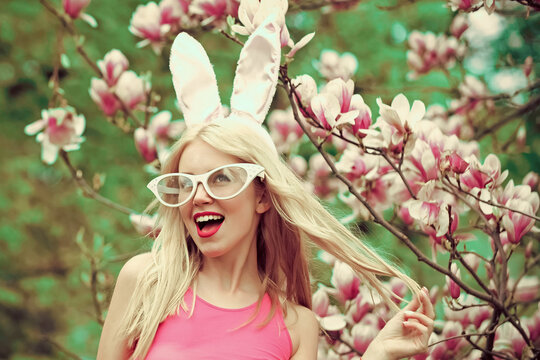 Funny crazy young woman in blossoming magnolia flower, spring. Happy easter. Sexy woman in bunny ears. Spring, nature and environment.