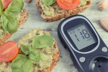 Glucometer with sugar level and sandwiches with paste of avocado. Healthy food as source omega...
