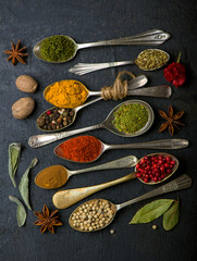 Various spices spoons on black table. Top view with copy space