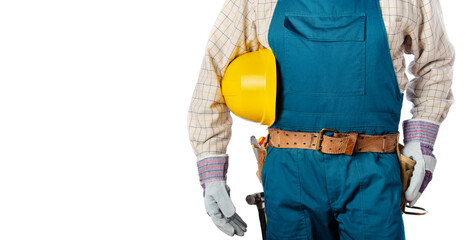 Middle aged contractor in overalls with tool belt holds yellow hard hat in his hands on white...