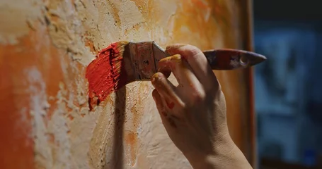 Fotobehang Schilderij Cinematic macro shot of female creative artist painter concentrated and inspired painting abstract picture with paint brush and oil colors on canvas while working on new masterpiece for exhibition.   © Kitreel