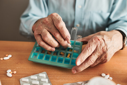 Senior Man Organizing His Medication Into Pill Dispenser. Senior Man Taking Pills From Box. Healthcare And Old Age Concept With Medicines. Medicaments On Table