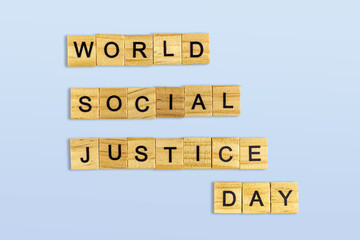 Top view of the word world social justice day laid out from square wooden tiles isolated on blue background. World and international day.
