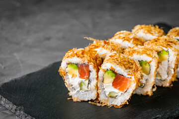 appetizing philadelphia sushi roll with tuna salmon avocado chips and cucumber on a black stone...