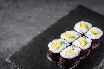 appetizing sushi maki roll avocado on a black stone plate