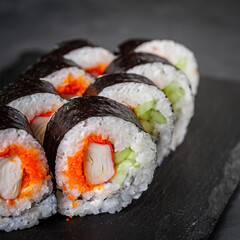 appetizing sushi roll futomaki with cucumber crab stick and masago on a black stone plate