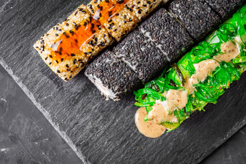 appetizing set of sushi roll on a black stone plate