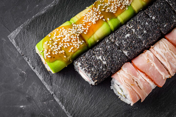 appetizing set of sushi roll on a black stone plate