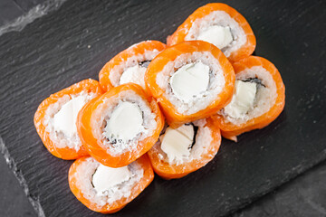 appetizing sushi roll philadelphia with cheese and salmon on a black stone plate