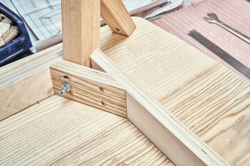 Corner of upside-down stylish new table of plywood, veneer and solid light ash in modern carpentry workshop extreme close view