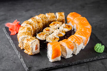 appetizing set of sushi roll on a black stone plate