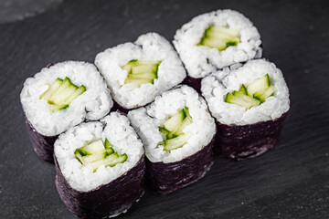 appetizing sushi roll maki with cucumber on a black stone plate