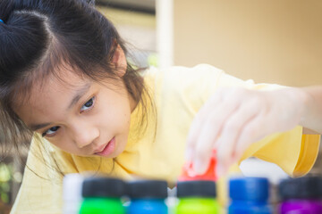 Asian little girl looking and pouring red ink to palette, Creativity children concepts