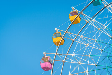 Colorful ferris wheel in an amusement park against blue sky