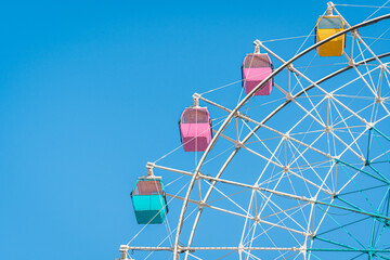 Colorful ferris wheel in an amusement park against blue sky