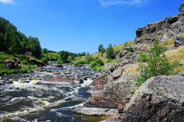 The mountain river flows among the green banks
