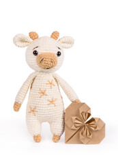 Knitted soft toy bull on white background and heart