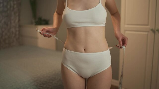 Young slim woman is measuring waist.