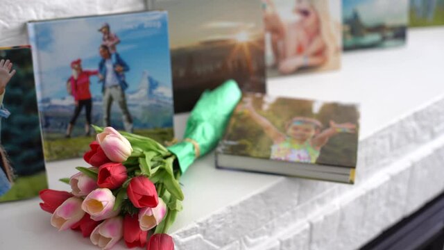 photo book and flowers tulips as a holiday gift lie on the shelf