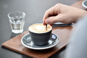 Detail of hand, glass and freshly roasted coffee.