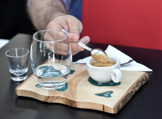 Detail of hand, glass and freshly roasted coffee.