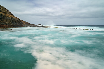 Sea landscape with rocks, waves and cloudy sky. Long exposure photo. Spain