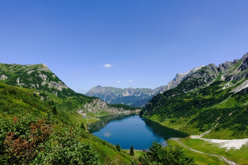 Fototapeta na wymiar view to a deep blue mountain lake with blue sky while hiking