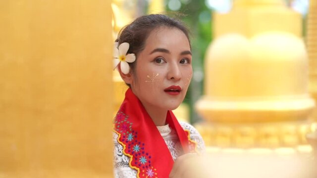 Young woman with traditional burmese with flower on hand at beautiful golden pagoda in Myanmar.
