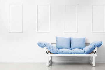 Stylish blue sofa near light wall