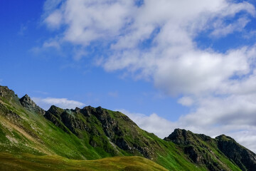 wonderful green rocky mountains and blue sky with clouds