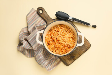 Cooking pot with pasta on color background