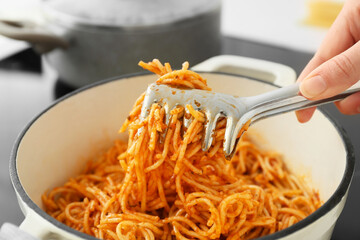 Woman cooking tasty pasta in kitchen