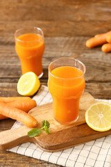 Glasses of healthy carrot juice with ingredients on table