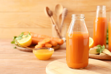 Bottle with tasty carrot juice on wooden table