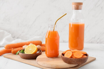 Bottles of tasty carrot juice on light background
