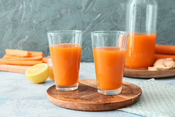 Plate with glasses of tasty carrot juice on color background
