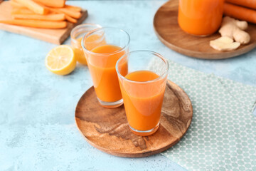 Plate with glasses of tasty carrot juice on color background