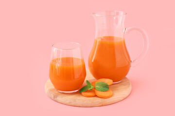 Board with tasty carrot juice on color background