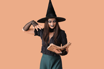 Evil young witch with spell book on color background