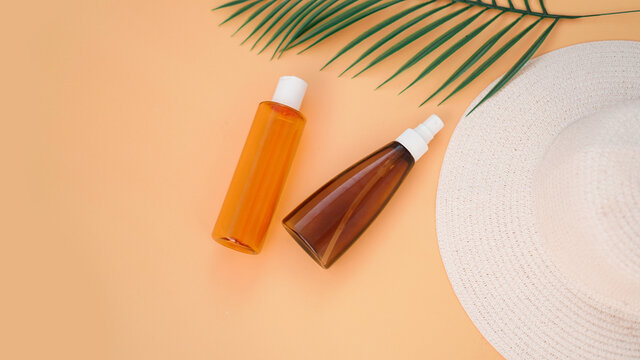 Sun cream, sun hat, lotion bottle on soft orange background. Sun protection. Summer time and holiday