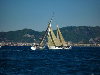 Fototapeta na wymiar sail boat yacht in race regatta with mountain background