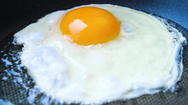 Close up slow motion video for the egg frying in the hot iron panto make fried egg for the breakfast 